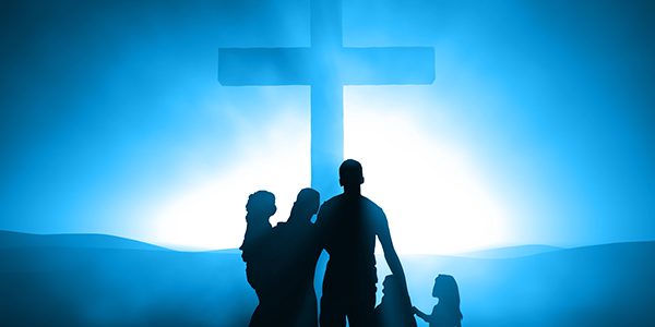 Silhouettes of a family at the Cross of Jesus.